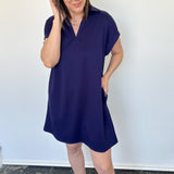 Athleisure dress that hits above the knees. Collared and short sleeve. Features a v neckline and pockets.  Navy in color.
