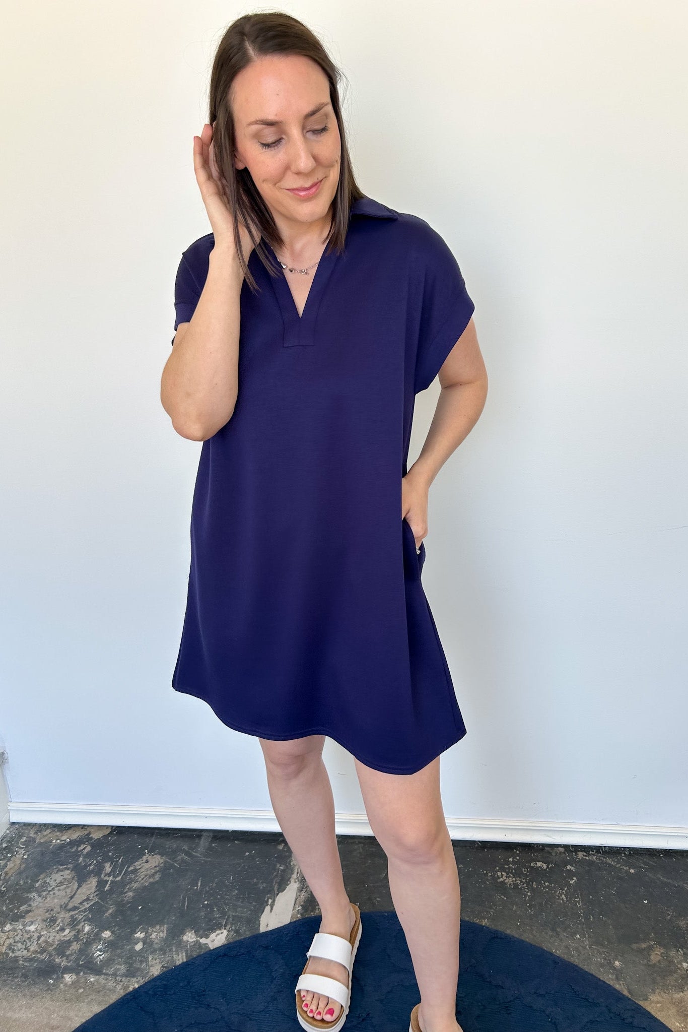 Athleisure dress that hits above the knees. Collared and short sleeve. Features a v neckline and pockets.  Navy in color.