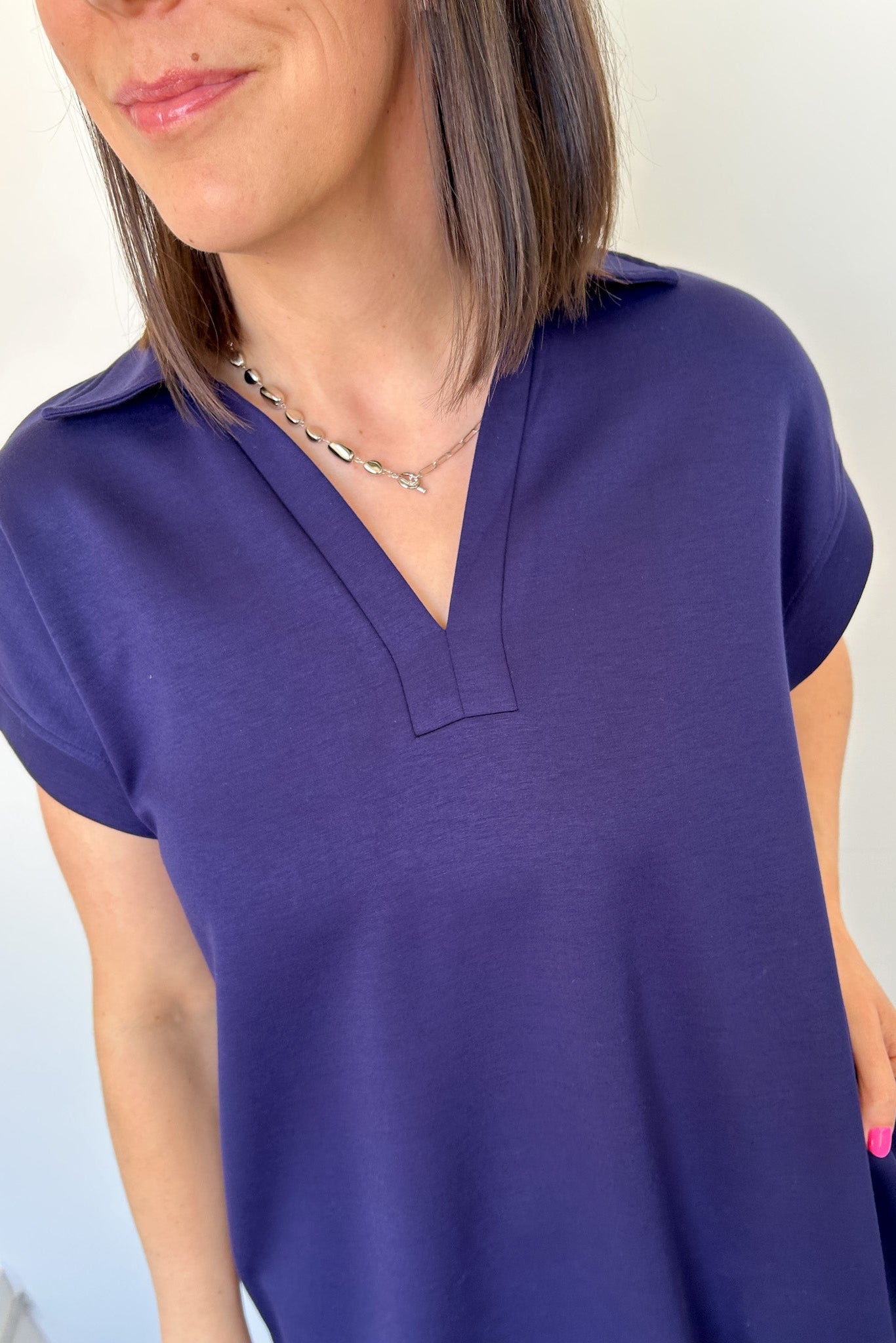 Athleisure dress that hits above the knees. Collared and short sleeve. Features a v neckline and pockets.  Navy in color.