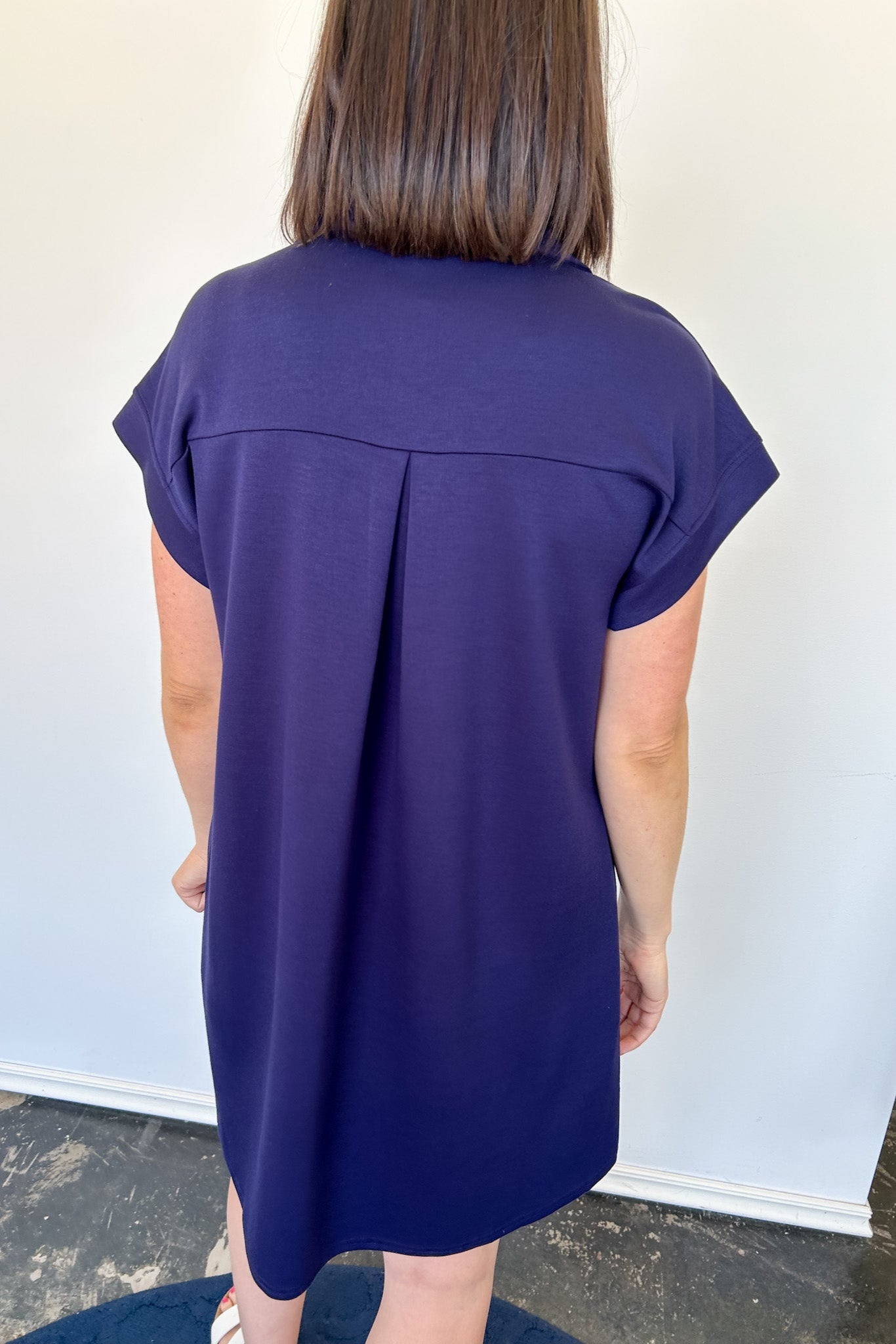 Athleisure dress that hits above the knees. Collared and short sleeve. Features a v neckline and pockets.  Navy in color.