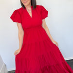 Maxi length dress with v neckline. Short sleeve with slightly bubbled sleeves. Tiered bottom. Elastic waist. Red in color.