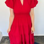 Maxi length dress with v neckline. Short sleeve with slightly bubbled sleeves. Tiered bottom. Elastic waist. Red in color.