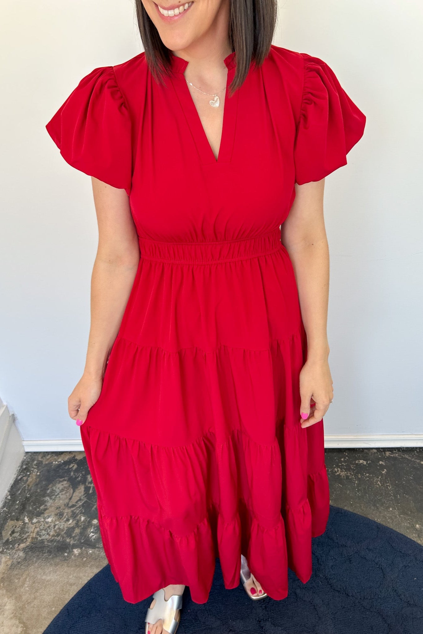 Maxi length dress with v neckline. Short sleeve with slightly bubbled sleeves. Tiered bottom. Elastic waist. Red in color.