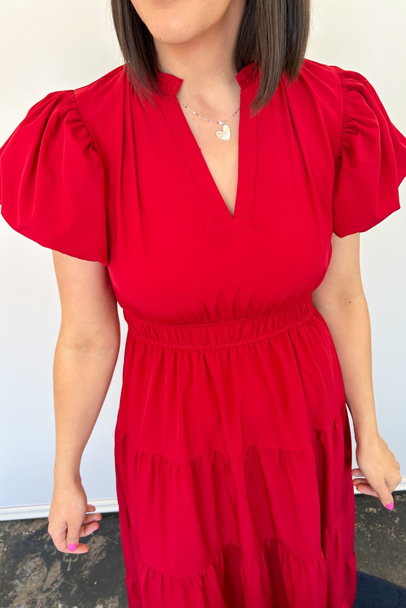 Maxi length dress with v neckline. Short sleeve with slightly bubbled sleeves. Tiered bottom. Elastic waist. Red in color.