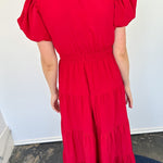 Maxi length dress with v neckline. Short sleeve with slightly bubbled sleeves. Tiered bottom. Elastic waist. Red in color.