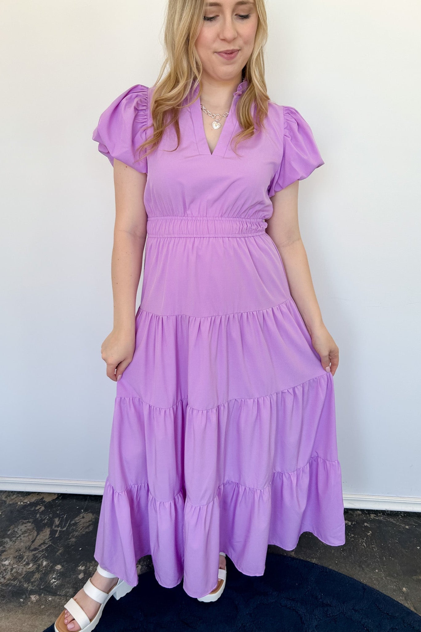 Maxi length dress with v neckline. Short sleeve with slightly bubbled sleeves. Tiered bottom. Elastic waist. Purple in color.