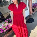 Maxi length dress with v neckline. Short sleeve with slightly bubbled sleeves. Tiered bottom. Elastic waist. Red in color.