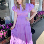 Maxi length dress with v neckline. Short sleeve with slightly bubbled sleeves. Tiered bottom. Elastic waist. Purple in color.