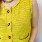 Button up vest with brown buttons. Pockets in the front. Braided detail around the tank sleeves and neckline, as well as the bottom of the top. Chartreuse in color.