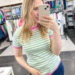 Striped top in a mint blue color with pink lining the neckline and around the short sleeves, as well as along the bottom. High neckline and slightly fitted style.