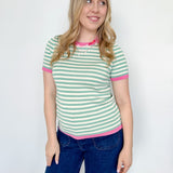 Striped top in a mint blue color with pink lining the neckline and around the short sleeves, as well as along the bottom. High neckline and slightly fitted style.