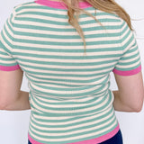 Striped top in a mint blue color with pink lining the neckline and around the short sleeves, as well as along the bottom. High neckline and slightly fitted style.