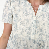 Short flowy sleeved top with button detailing. Cream in color with light blue floral pattern. Babydoll style.