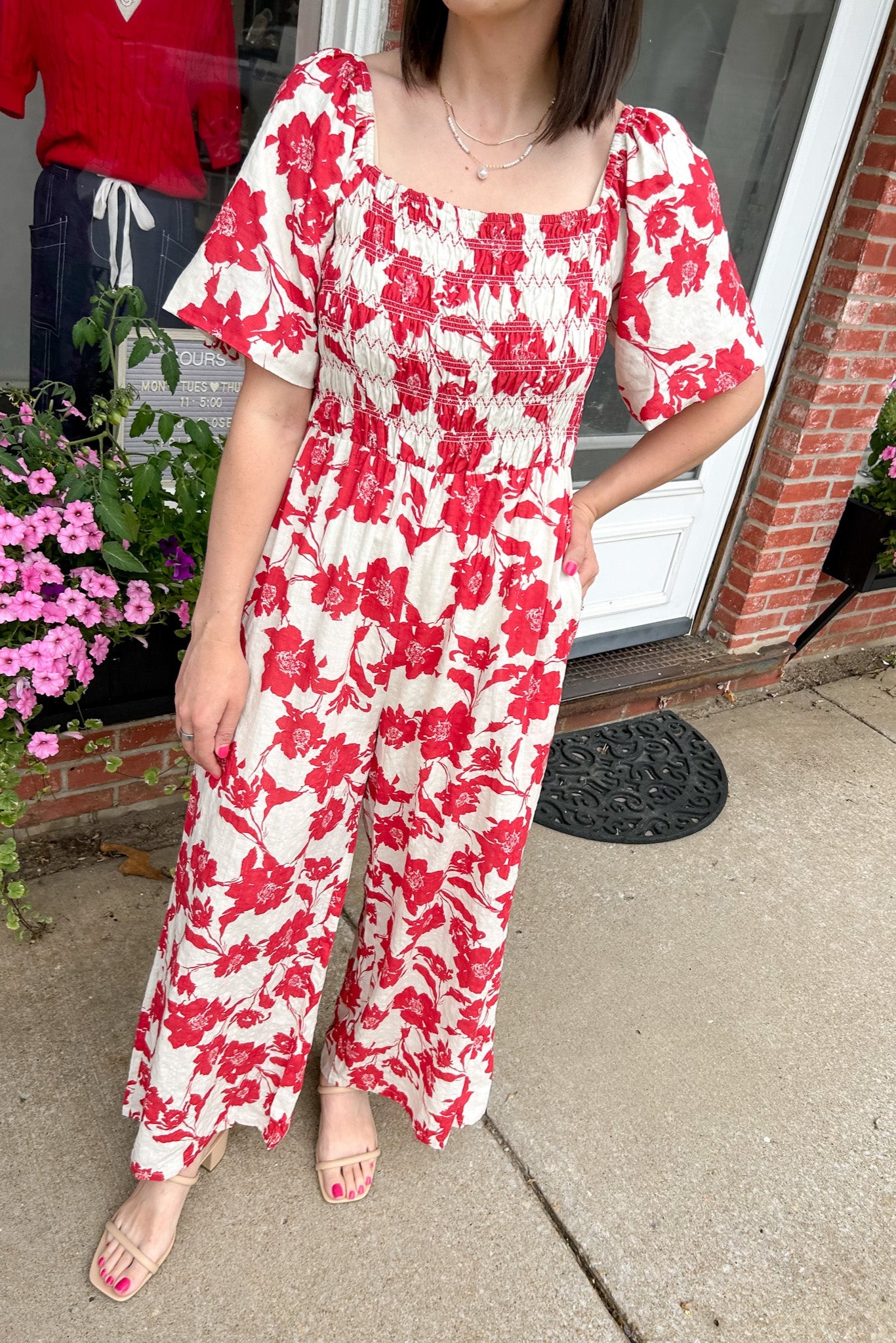 Red and white floral jumpsuit with square neckline. Short sleeved. Wide leg with smocked top. 