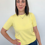 Woman wearing a yellow t-shirt and blue jeans against a white background