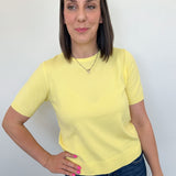 Woman wearing a yellow t-shirt and blue jeans against a white background