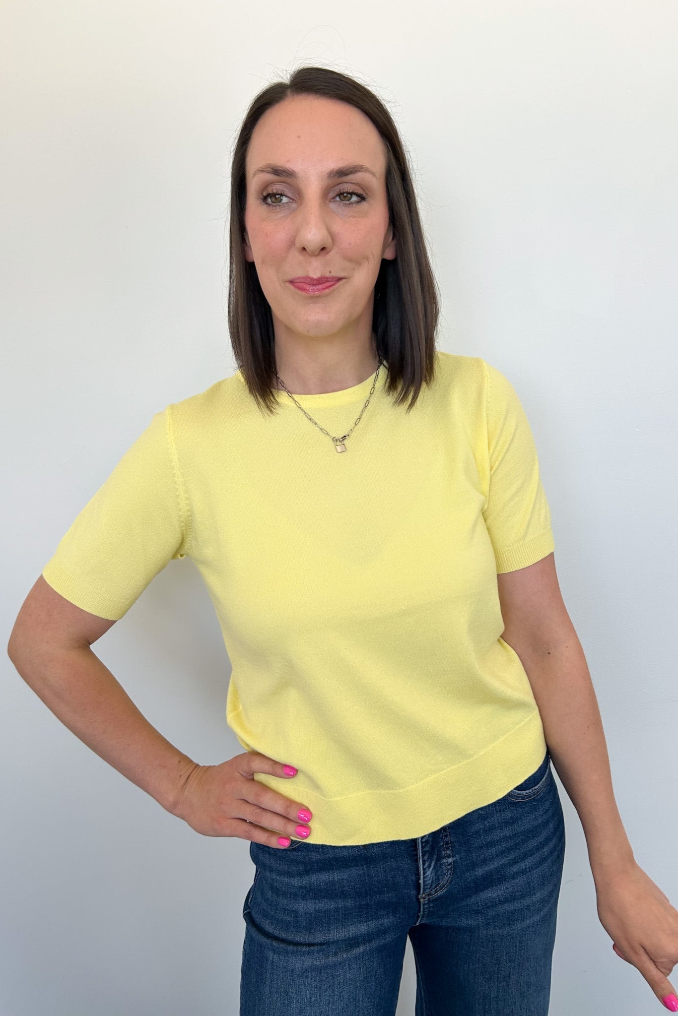 Woman wearing a yellow t-shirt and blue jeans against a white background