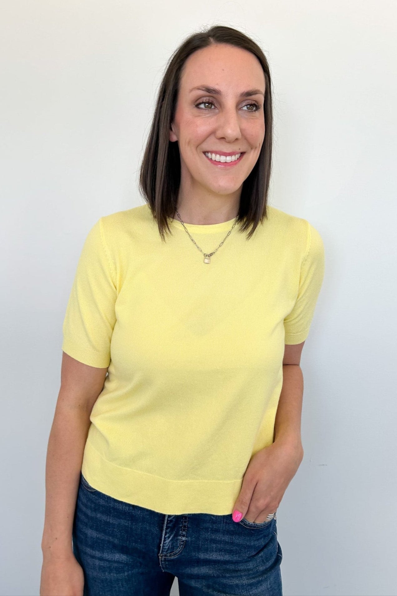 Woman wearing a yellow shirt and blue jeans against a white background