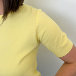 Person wearing a yellow shirt against a plain background