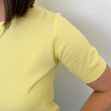 Person wearing a yellow shirt against a plain background