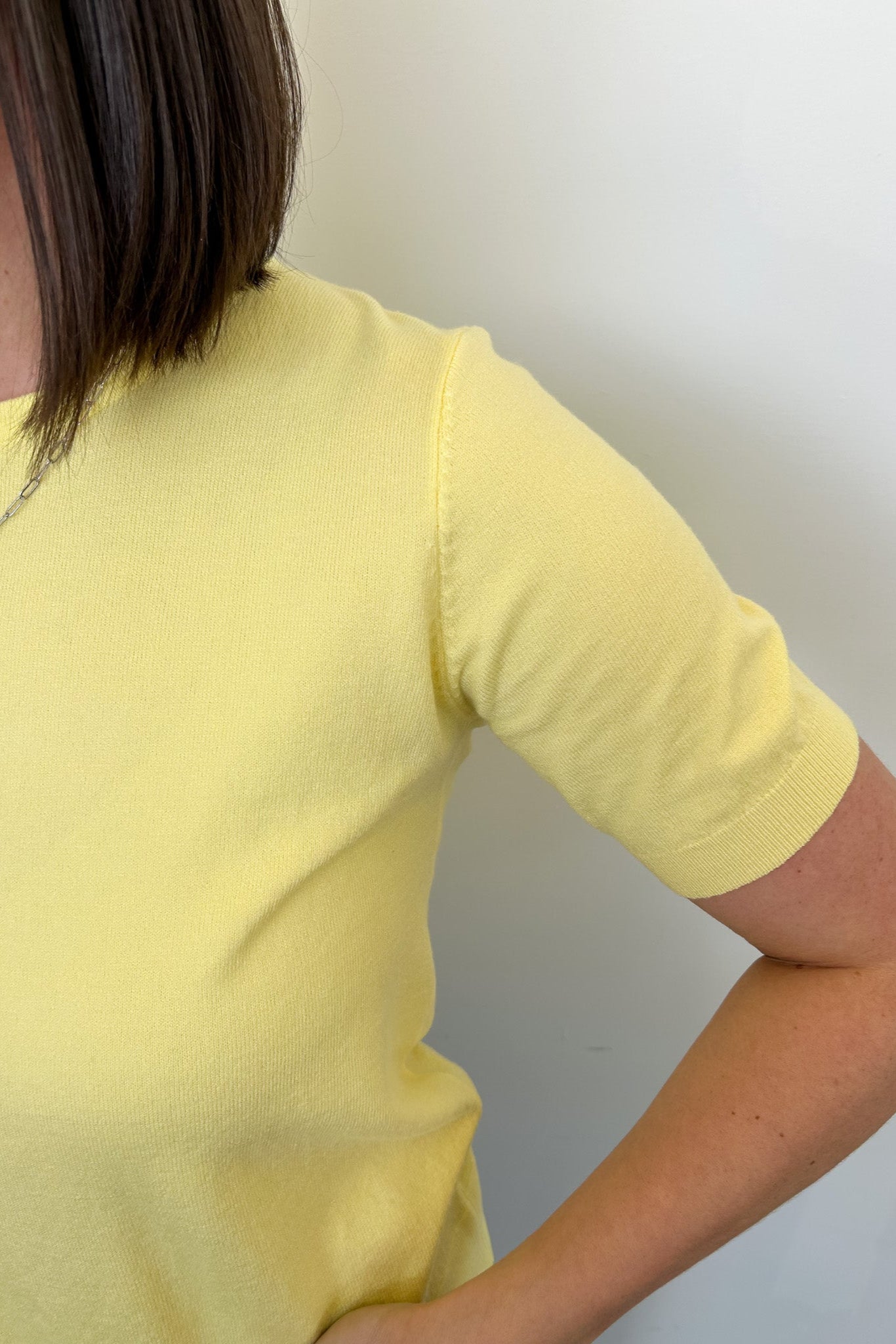 Person wearing a yellow shirt against a plain background