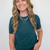 Woman wearing a teal shirt and beige pants against a white background