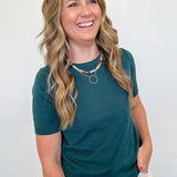 Woman wearing a teal shirt and beige pants against a white background