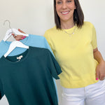 Woman holding three shirts on hangers against a white background