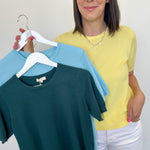 Woman holding two shirts on a hanger against a white background