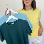 Woman holding two shirts on a hanger against a white background