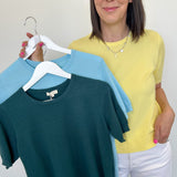Woman holding two shirts on a hanger against a white background