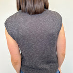 Person wearing a gray sleeveless sweater against a white background