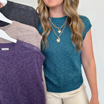 Woman holding a rack of sweaters with a plain background