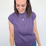 Woman wearing a deep summer purple sleeveless sweater against a white background