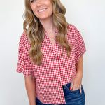 Woman wearing a red and white checkered shirt and blue jeans against a white background