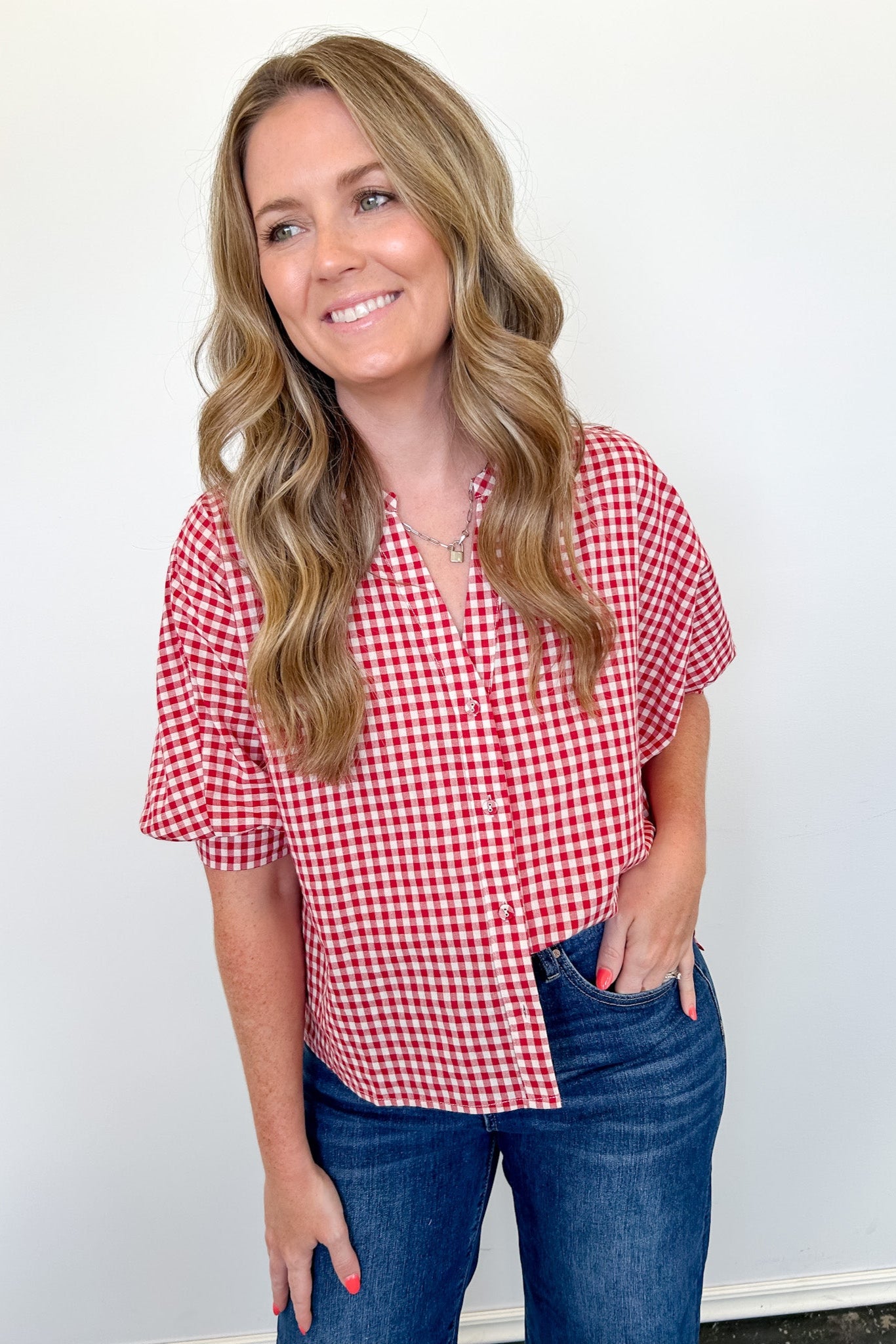 Woman wearing a red and white checkered shirt and blue jeans against a white background