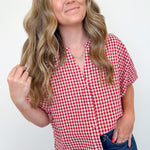Woman wearing a red and white checkered shirt against a plain background