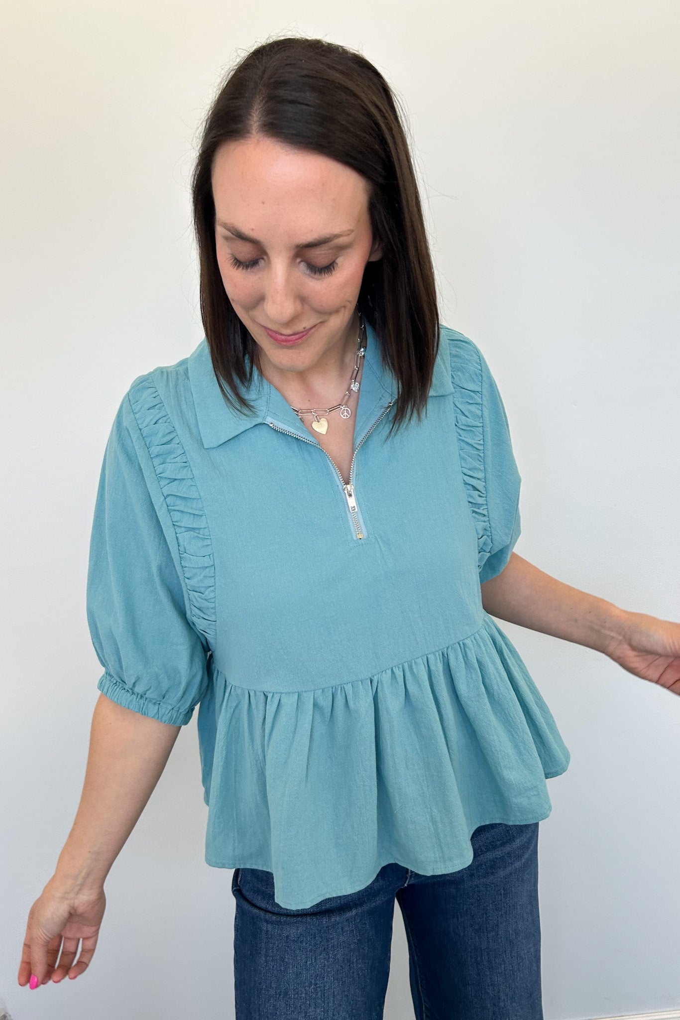 Woman wearing a light blue blouse with ruffled details against a white background