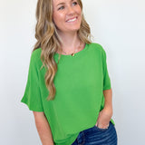 Woman wearing a green top and blue jeans against a white background