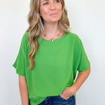 Woman wearing a green top and blue jeans against a white background