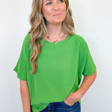 Woman wearing a green top and blue jeans against a white background