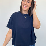 Woman wearing a navy blue t-shirt and blue jeans against a white background