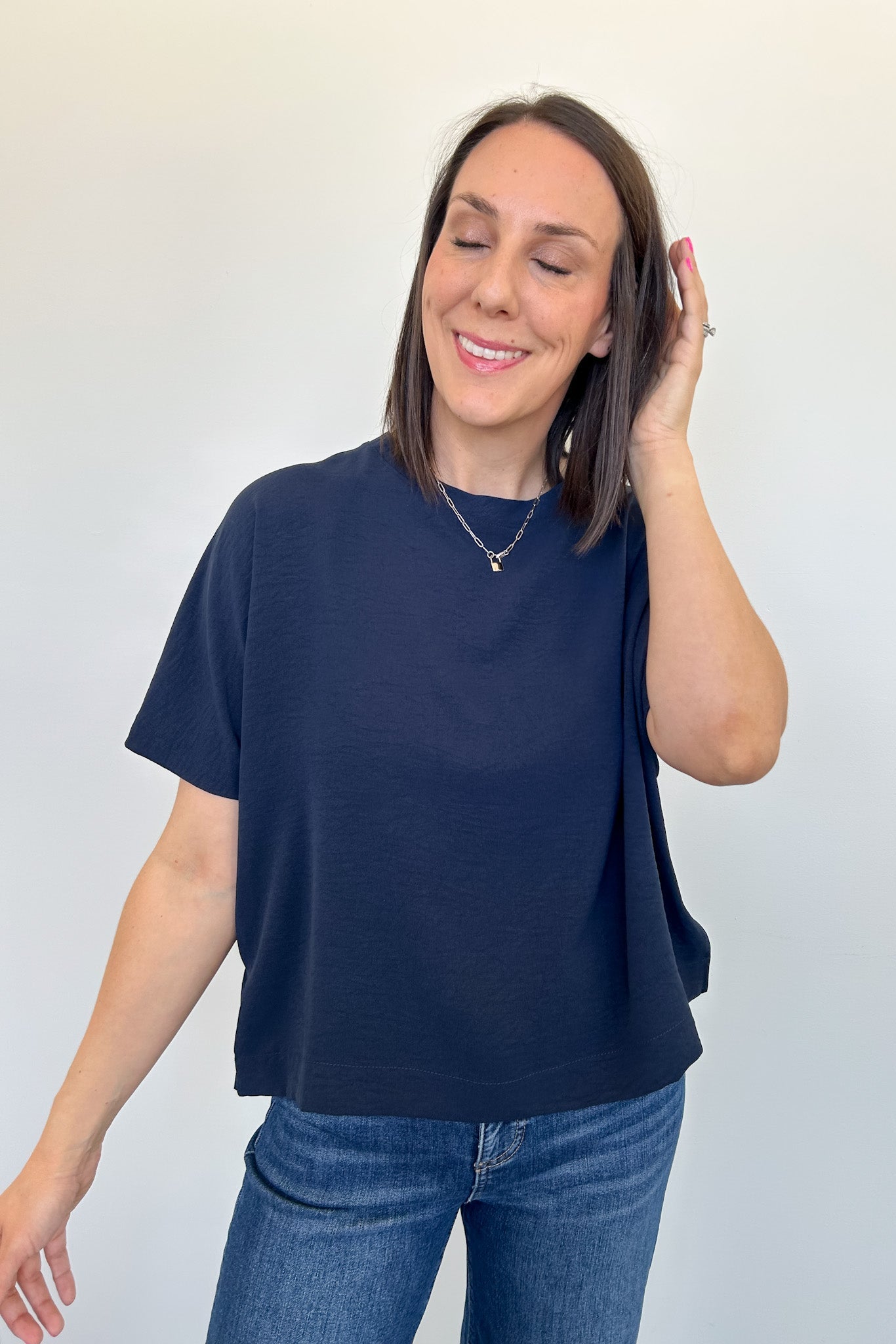 Woman wearing a navy blue t-shirt and blue jeans against a white background