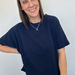 Woman wearing a navy blue t-shirt and jeans against a plain background