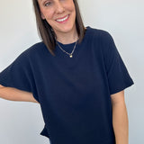 Woman wearing a navy blue t-shirt and jeans against a plain background