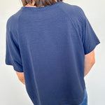 Person wearing a blue t-shirt and jeans against a white wall