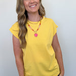 Woman wearing a yellow top and blue jeans against a white background