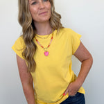 Woman wearing a yellow top and blue jeans against a white background