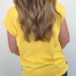 Person wearing a yellow sleeveless top with a plain background