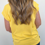 Person wearing a yellow sleeveless top with a plain background